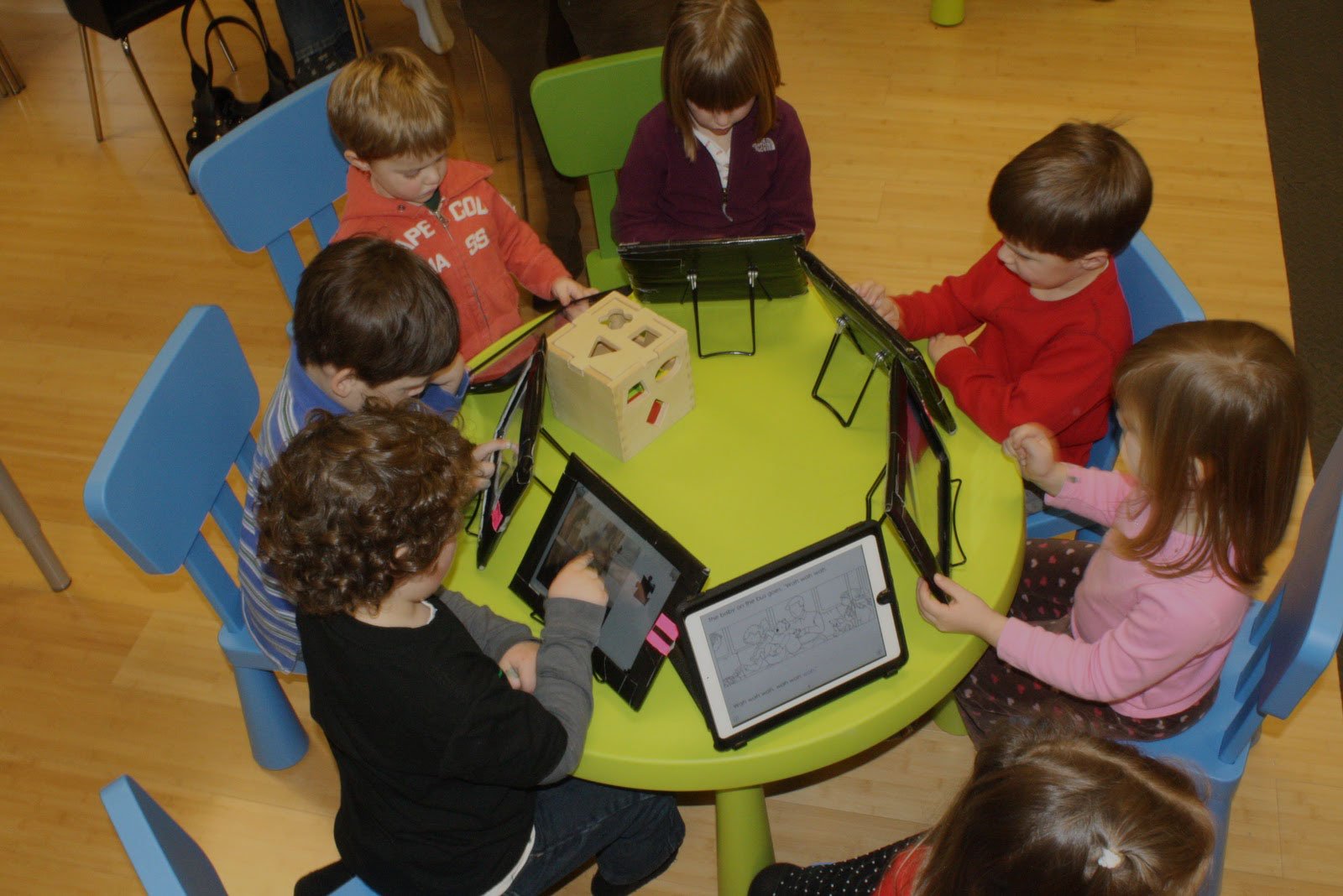 Students sitting at table in their classroom using tablets for learning