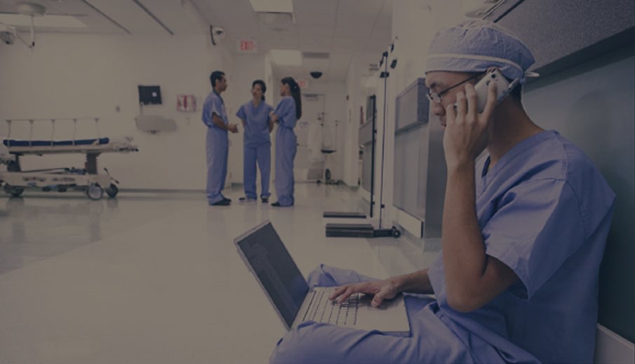 Medical Professional using laptop and cell phone in hospital setting