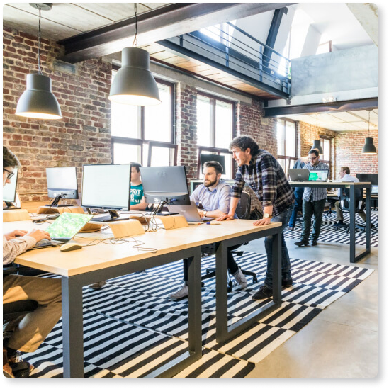 Two people looking at a desktop computer inside a modern office